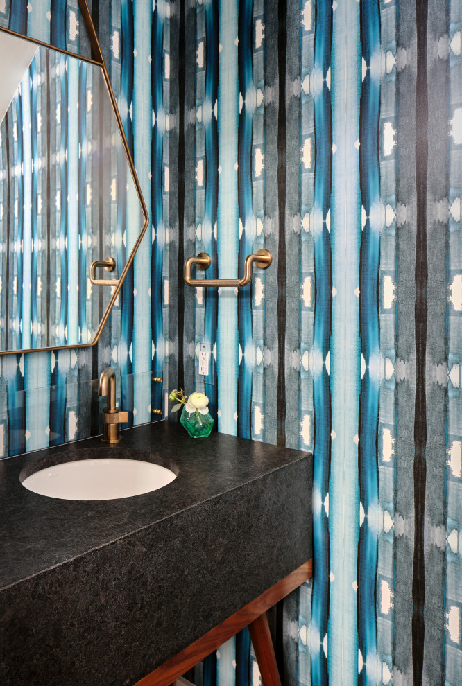Inredning av ett retro litet svart svart toalett, med öppna hyllor, skåp i mellenmörkt trä, blå väggar, mellanmörkt trägolv, ett undermonterad handfat, granitbänkskiva och brunt golv