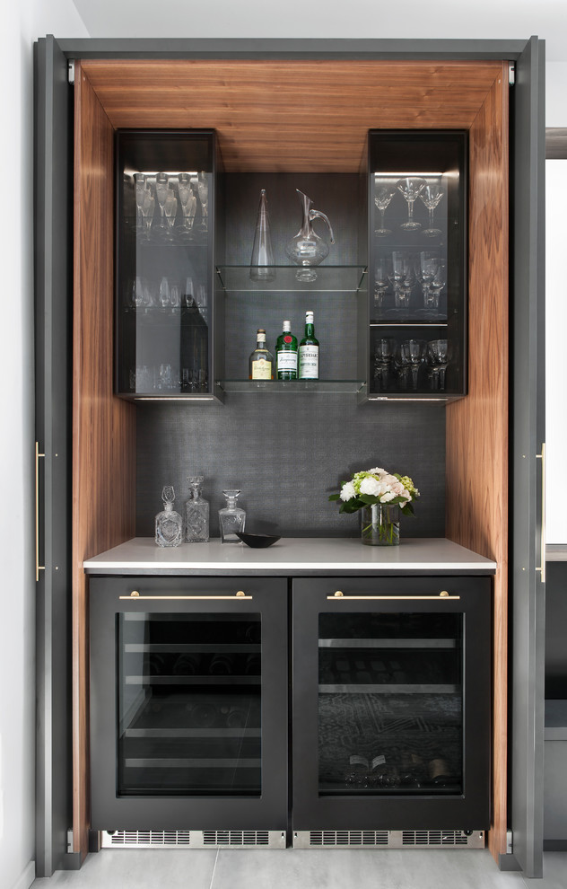 Small contemporary single-wall home bar in Toronto with no sink, glass-front cabinets, black cabinets, black splashback, grey floor and white benchtop.