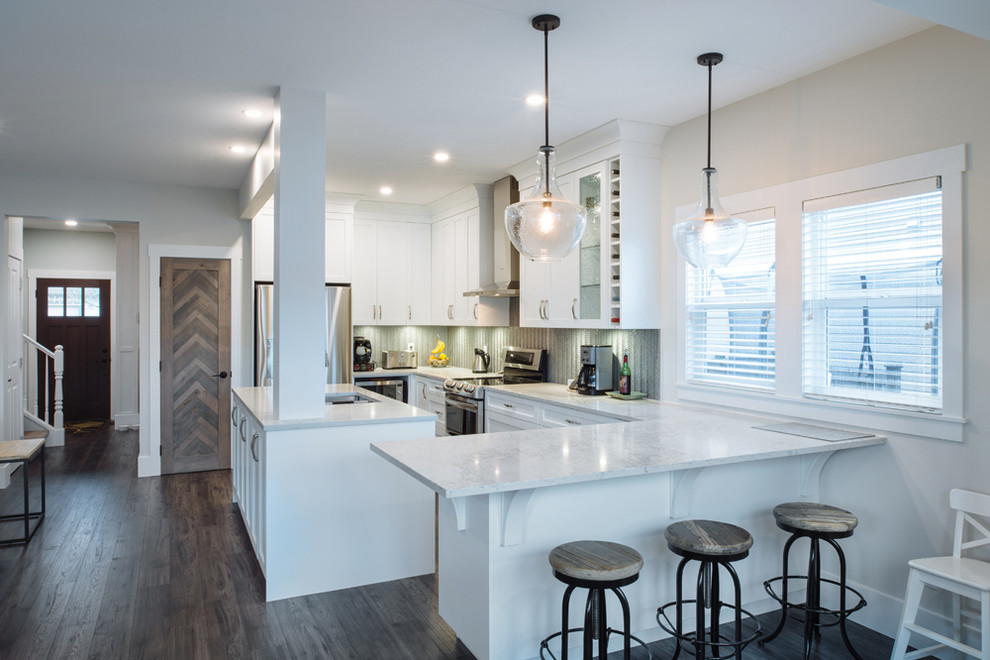 This is an example of a large modern l-shaped eat-in kitchen in Vancouver with an undermount sink, shaker cabinets, white cabinets, glass benchtops, grey splashback, glass sheet splashback, stainless steel appliances, laminate floors, with island and grey floor.