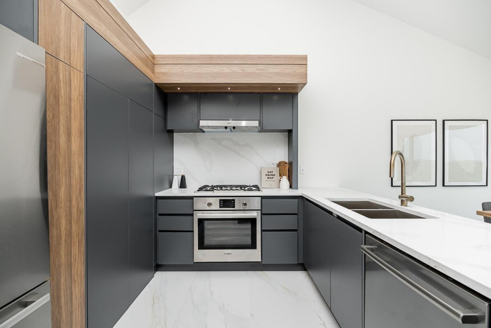 Inspiration for a mid-sized transitional u-shaped ceramic tile, multicolored floor and vaulted ceiling kitchen pantry remodel in Vancouver with an undermount sink, flat-panel cabinets, gray cabinets, quartzite countertops, white backsplash, ceramic backsplash, stainless steel appliances, an island and white countertops