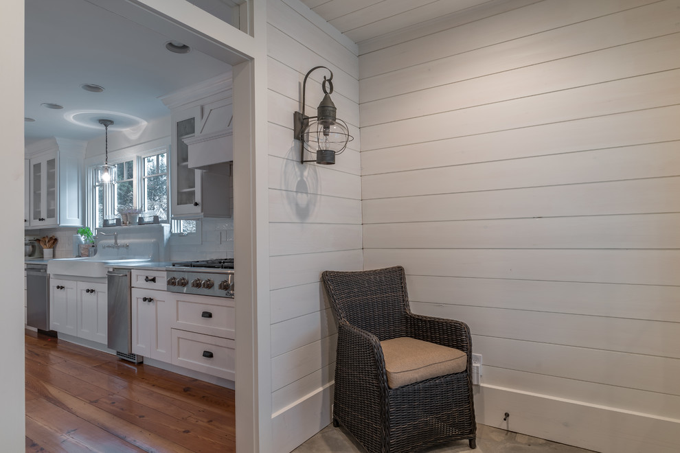 Inspiration for a mid-sized transitional medium tone wood floor kitchen remodel with a farmhouse sink, recessed-panel cabinets, white cabinets, marble countertops, white backsplash, subway tile backsplash, stainless steel appliances and an island