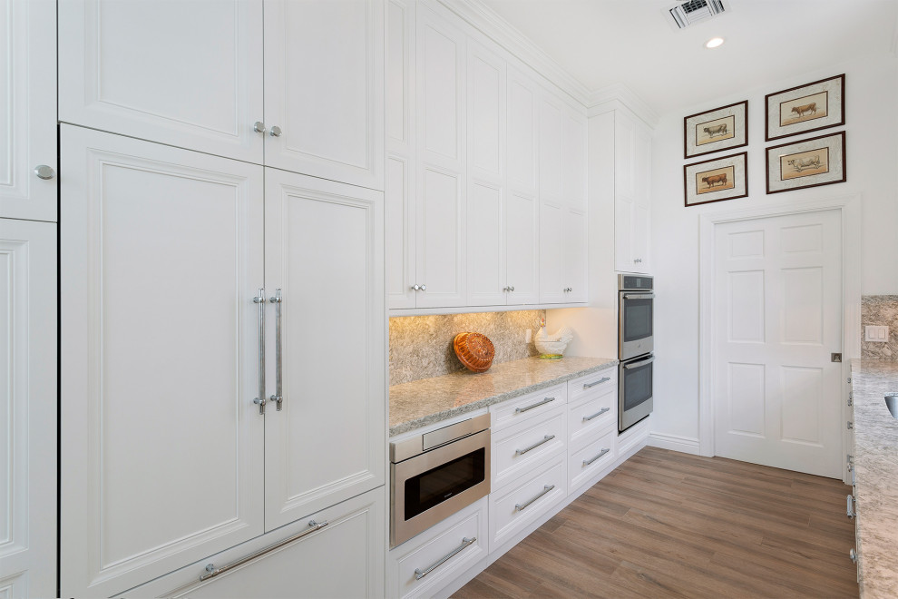 Open concept kitchen - large transitional galley medium tone wood floor and beige floor open concept kitchen idea in Miami with an undermount sink, recessed-panel cabinets, white cabinets, marble countertops, beige backsplash, mosaic tile backsplash, stainless steel appliances, an island and beige countertops