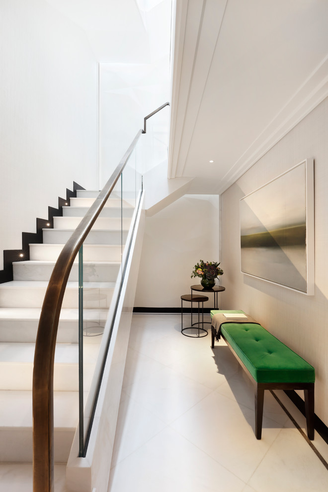 This is an example of a large contemporary hallway in London with white walls and marble floors.