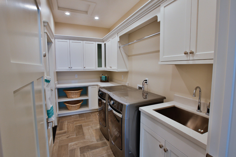 Large transitional galley dedicated laundry room in Salt Lake City with an undermount sink, shaker cabinets, white cabinets, beige walls, a side-by-side washer and dryer, quartzite benchtops and porcelain floors.