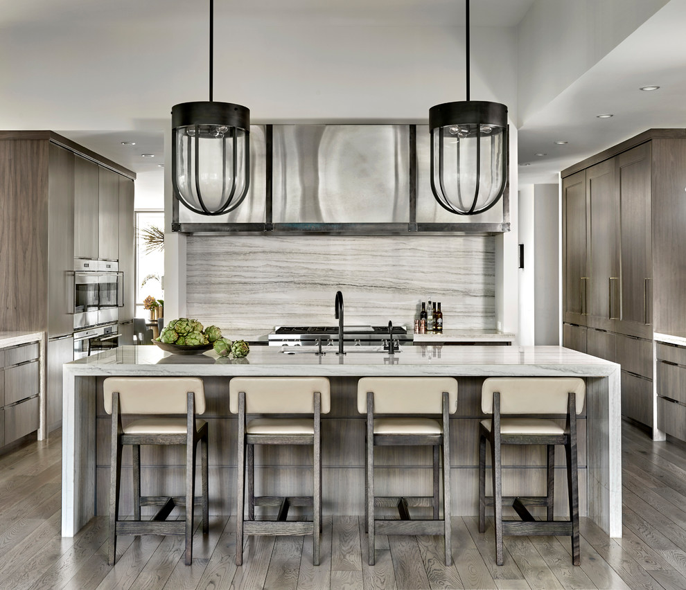 Photo of a contemporary u-shaped kitchen in Chicago with an undermount sink, shaker cabinets, dark wood cabinets, grey splashback, stainless steel appliances, medium hardwood floors, with island, grey floor and grey benchtop.