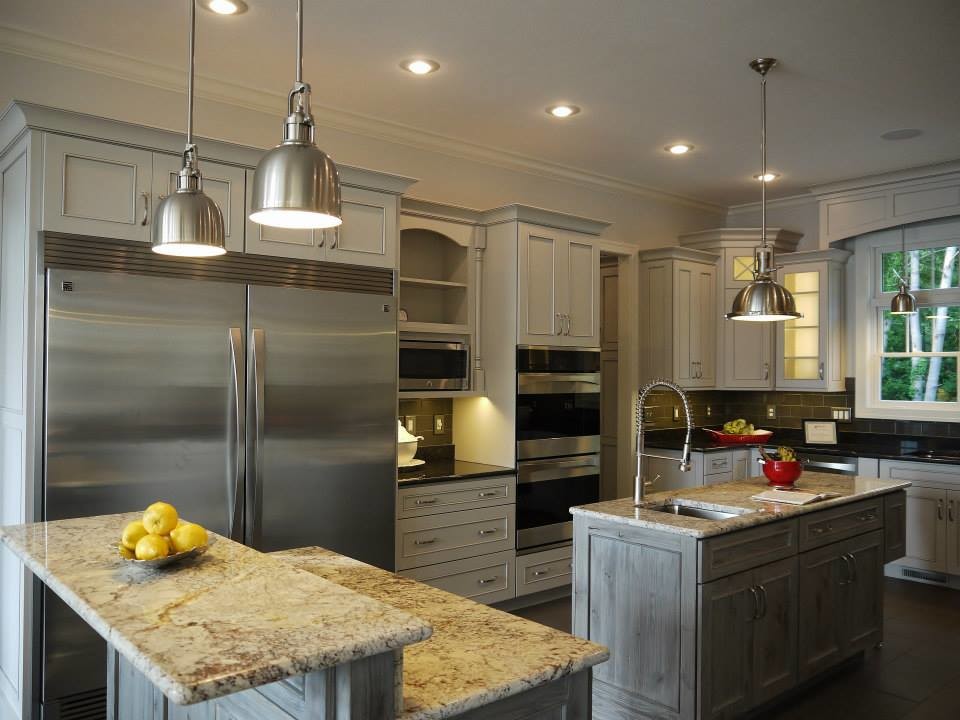 This is an example of a large transitional u-shaped kitchen in Grand Rapids with an undermount sink, recessed-panel cabinets, white cabinets, stainless steel appliances and multiple islands.