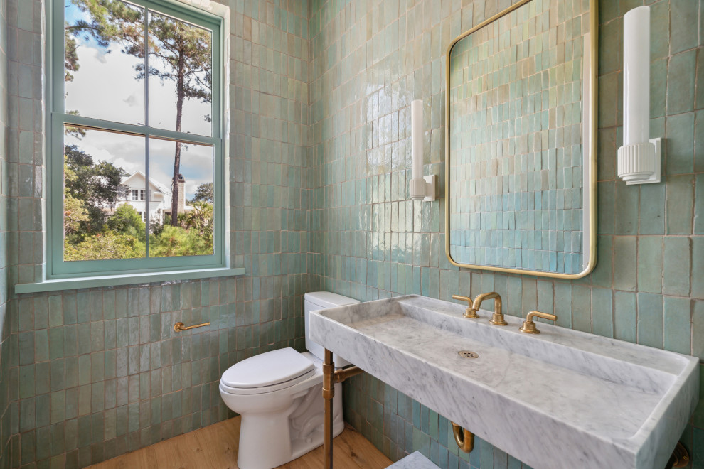 На фото: туалет в стиле модернизм с унитазом-моноблоком, зеленой плиткой, терракотовой плиткой, зелеными стенами, светлым паркетным полом, консольной раковиной, мраморной столешницей и напольной тумбой с