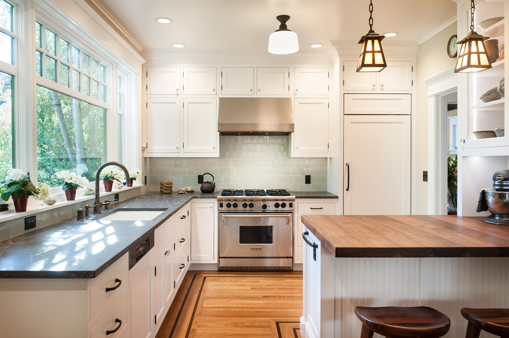 Design ideas for a small traditional l-shaped open plan kitchen in San Francisco with a single-bowl sink, beaded inset cabinets, white cabinets, soapstone benchtops, green splashback, ceramic splashback, white appliances, light hardwood floors and with island.