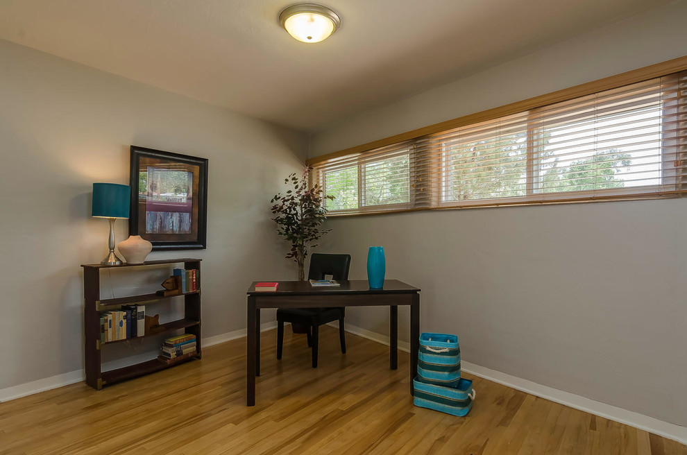 Small home office in Albuquerque with grey walls, light hardwood floors, no fireplace and a freestanding desk.