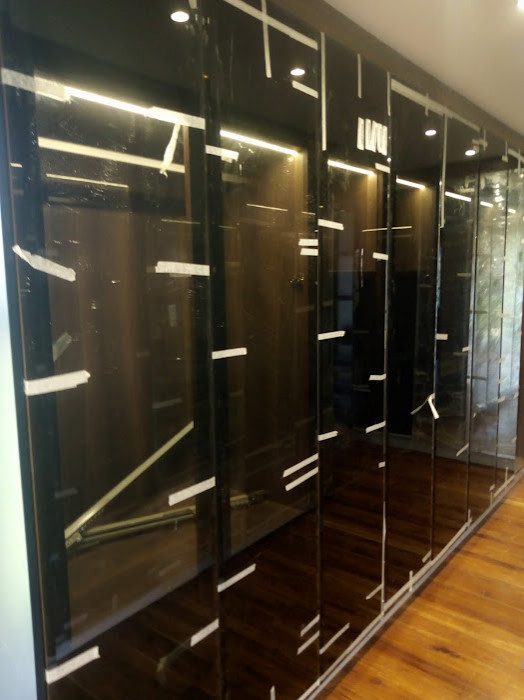 Foto på ett litet funkis walk-in-closet för könsneutrala, med luckor med glaspanel, skåp i mörkt trä, laminatgolv och brunt golv