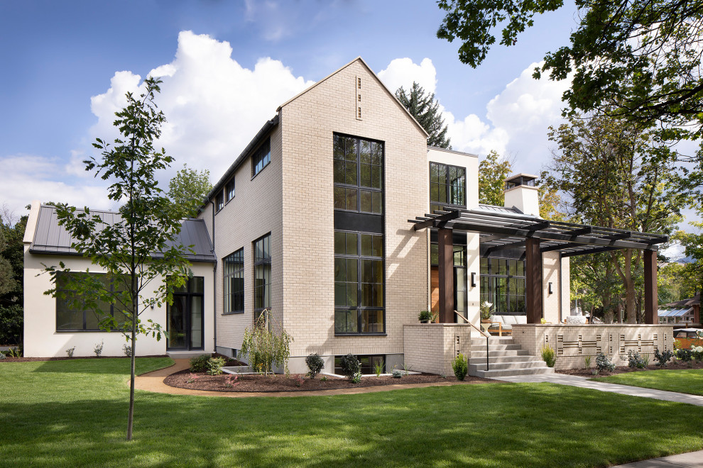 Idée de décoration pour une façade de maison beige minimaliste en brique à un étage avec un toit en métal.