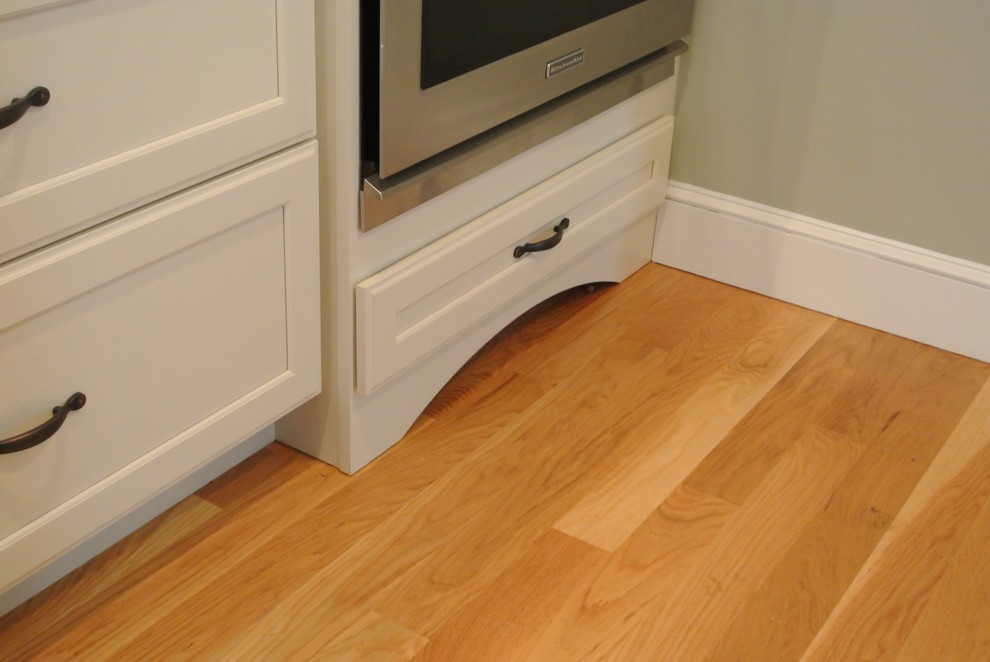 Transitional galley light wood floor eat-in kitchen photo in Boston with an undermount sink, shaker cabinets, white cabinets, wood countertops, white backsplash, ceramic backsplash, stainless steel appliances, an island and brown countertops