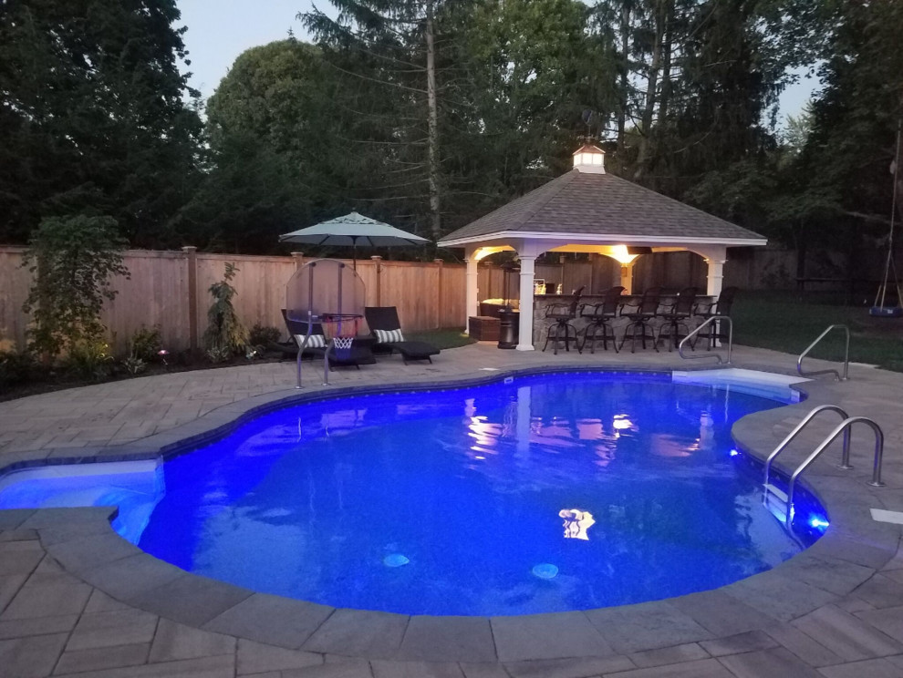 Large traditional backyard pool in Philadelphia with natural stone pavers.