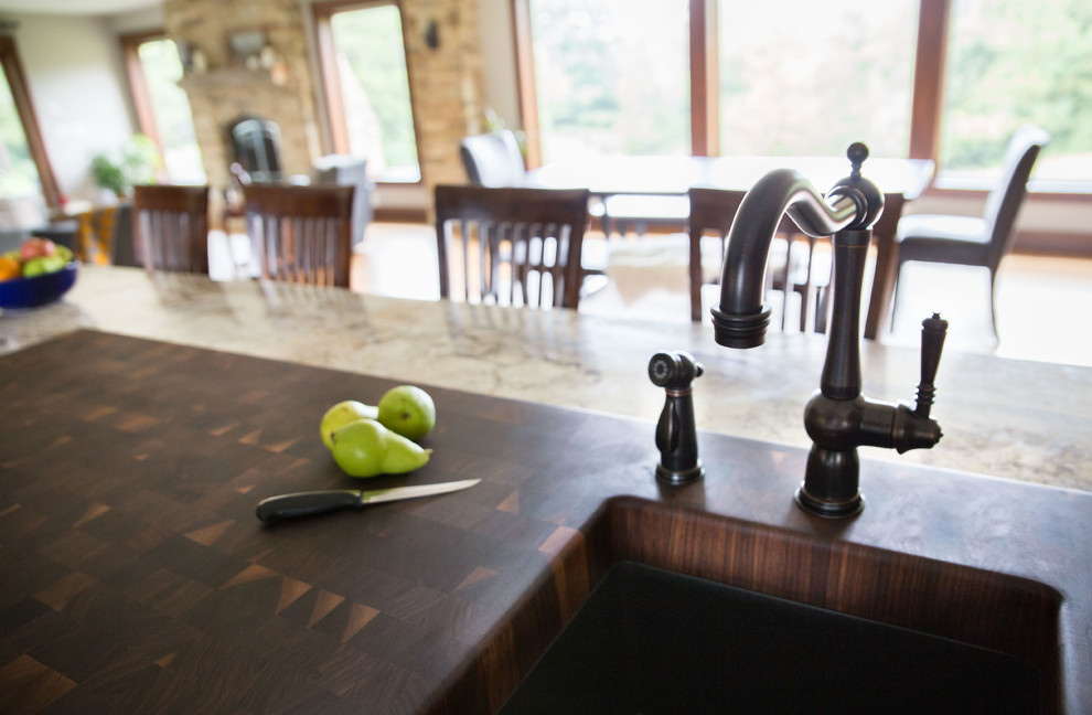 Example of a mid-sized mountain style galley light wood floor open concept kitchen design in Cedar Rapids with recessed-panel cabinets, medium tone wood cabinets, granite countertops, black appliances, an island, an undermount sink and multicolored countertops