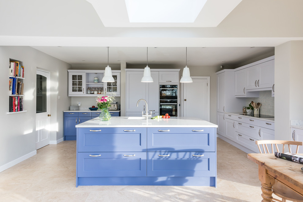 Inspiration for a large transitional single-wall open plan kitchen in Buckinghamshire with a double-bowl sink, shaker cabinets, blue cabinets, quartzite benchtops, white splashback, subway tile splashback, black appliances, porcelain floors, with island, beige floor and yellow benchtop.