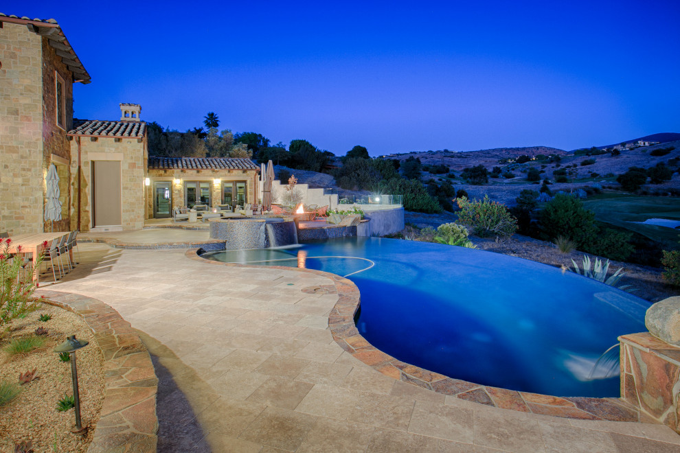 Photo of a large mediterranean drought-tolerant and full sun backyard stone landscaping in San Diego with a fire pit.