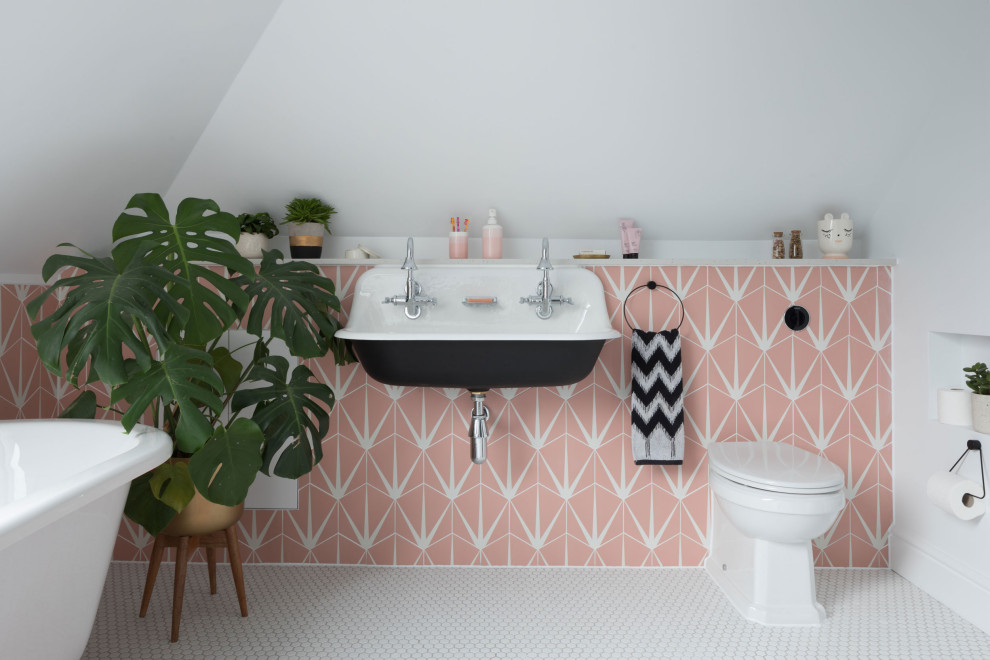 Photo of a large transitional kids bathroom in Kent with pink tile, white tile, a hinged shower door, a double vanity, black cabinets, a freestanding tub, a one-piece toilet, white walls, mosaic tile floors, a wall-mount sink and white floor.