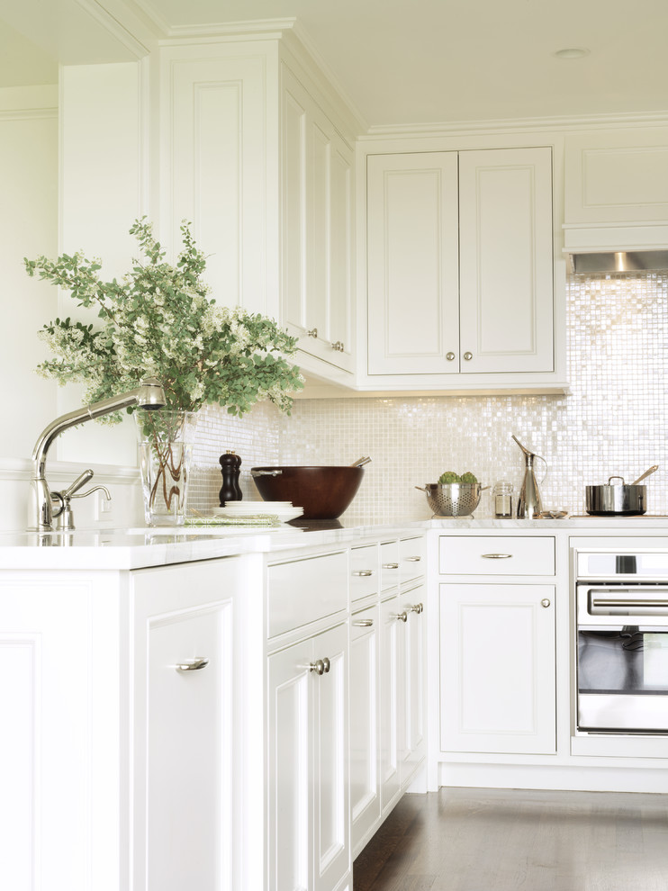 This is an example of a traditional kitchen in Boston with stainless steel appliances, recessed-panel cabinets, white cabinets and white splashback.