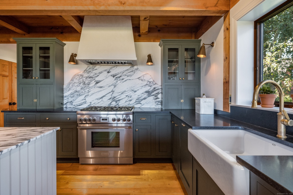 Eat-in kitchen - mid-sized rustic u-shaped medium tone wood floor, brown floor and wood ceiling eat-in kitchen idea in Boston with a farmhouse sink, recessed-panel cabinets, green cabinets, granite countertops, white backsplash, marble backsplash, stainless steel appliances, two islands and black countertops
