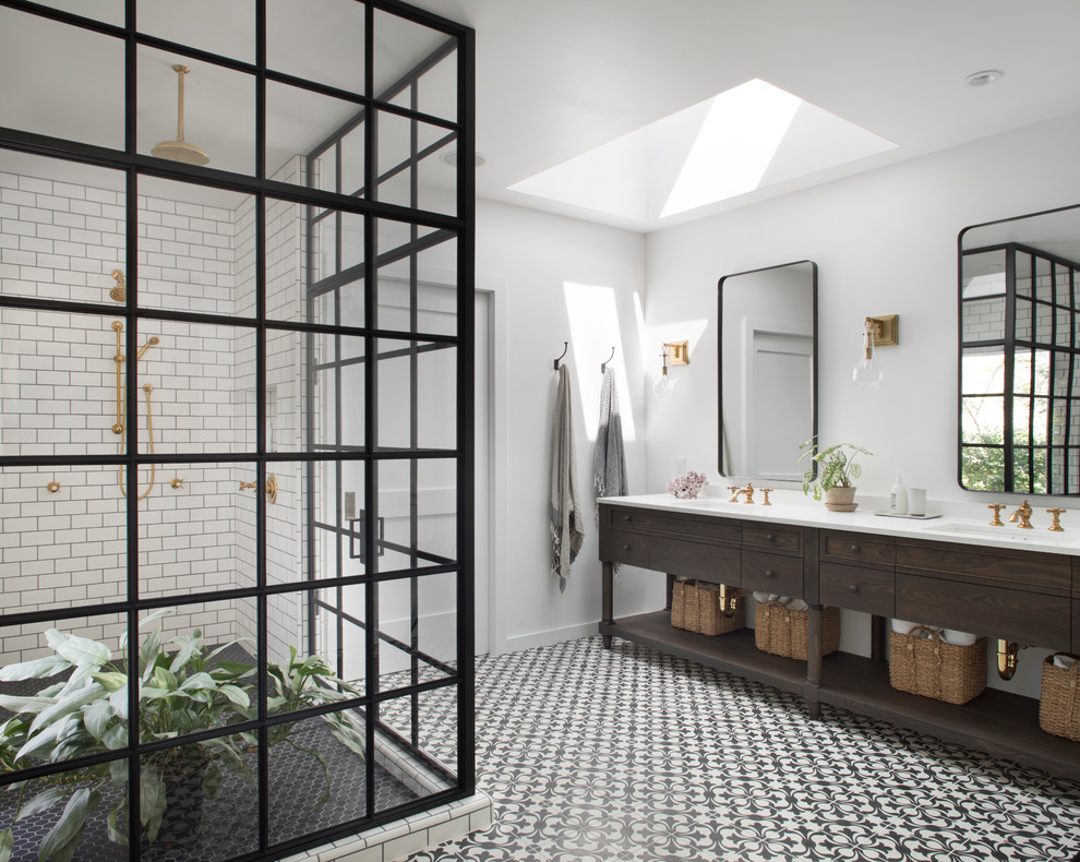 Photo of a country bathroom in San Francisco with dark wood cabinets, a corner shower, white tile, subway tile, white walls, an undermount sink, a hinged shower door and flat-panel cabinets.