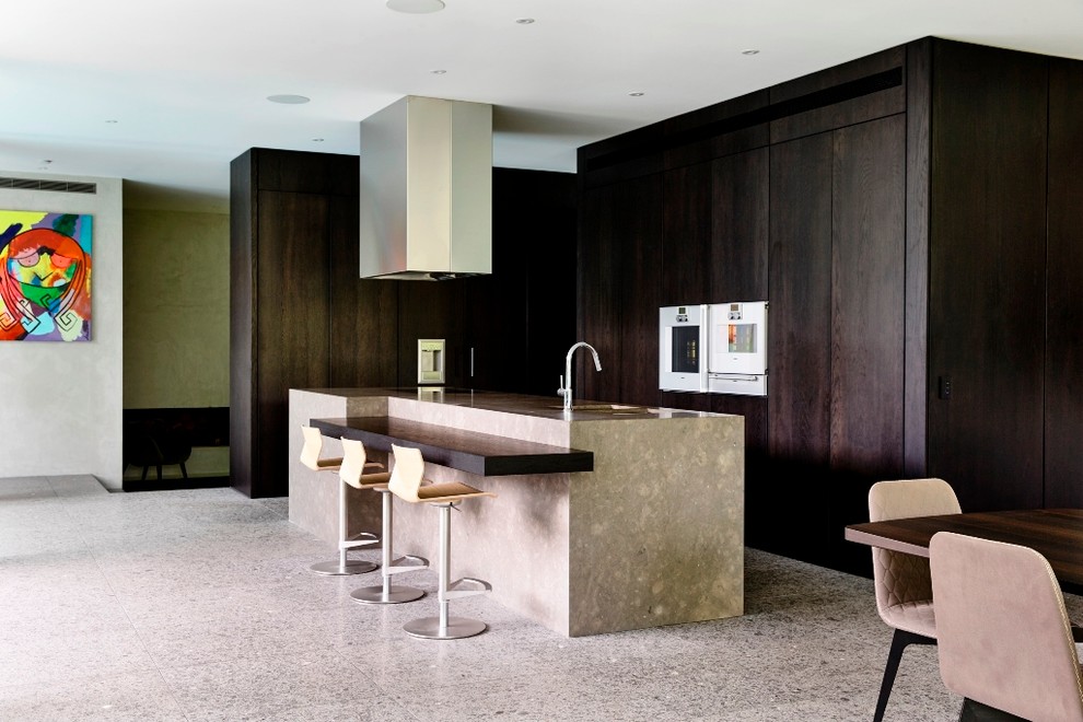Contemporary l-shaped kitchen in Melbourne with a double-bowl sink, dark wood cabinets, white appliances, limestone floors and with island.