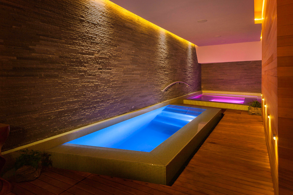 This is an example of a contemporary indoor rectangular pool in Other with a hot tub.