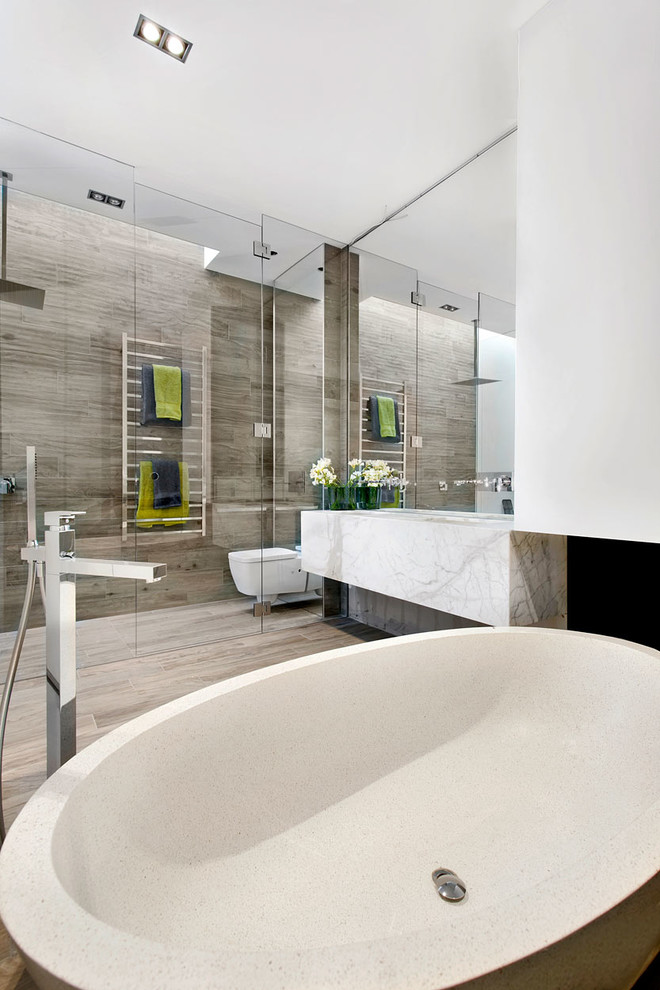 Design ideas for a mid-sized contemporary master bathroom in Melbourne with flat-panel cabinets, white cabinets, a freestanding tub, a curbless shower, a wall-mount toilet, brown tile, porcelain tile, white walls, porcelain floors, an undermount sink, marble benchtops, brown floor and a hinged shower door.