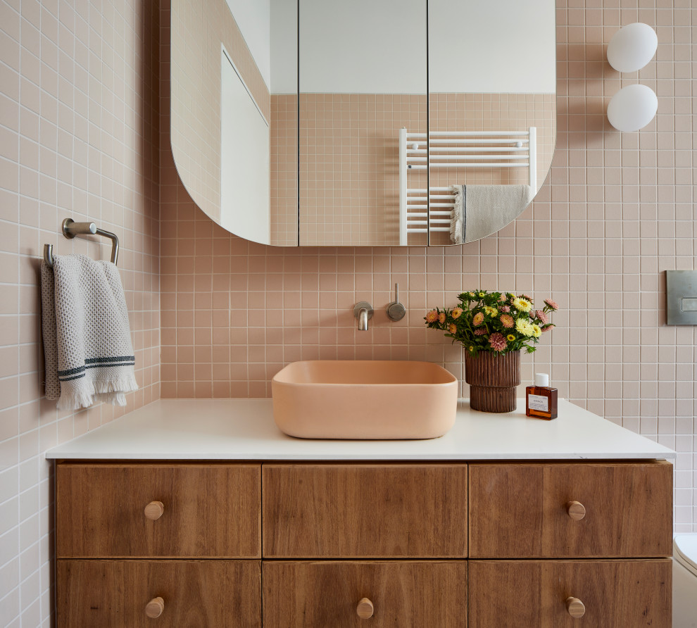 Свежая идея для дизайна: большая детская ванная комната в современном стиле с плоскими фасадами, коричневыми фасадами, отдельно стоящей ванной, открытым душем, унитазом-моноблоком, розовой плиткой, керамогранитной плиткой, белыми стенами, полом из терраццо, настольной раковиной, столешницей из искусственного камня, разноцветным полом, открытым душем, белой столешницей, тумбой под одну раковину и подвесной тумбой - отличное фото интерьера