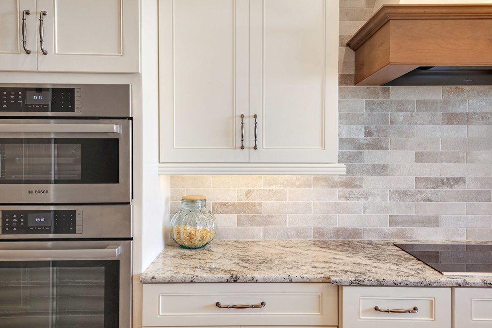 Large transitional u-shaped travertine floor and beige floor open concept kitchen photo in Phoenix with a farmhouse sink, recessed-panel cabinets, white cabinets, granite countertops, gray backsplash, porcelain backsplash, stainless steel appliances, an island and multicolored countertops