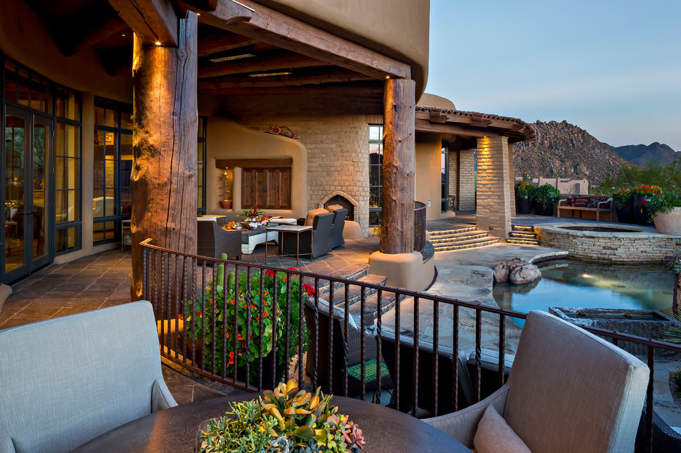 Photo of a mid-sized backyard patio in Phoenix with a fire feature, natural stone pavers and a roof extension.