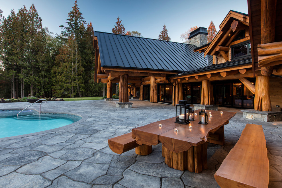 Example of a mountain style backyard stone patio design in Vancouver with a roof extension