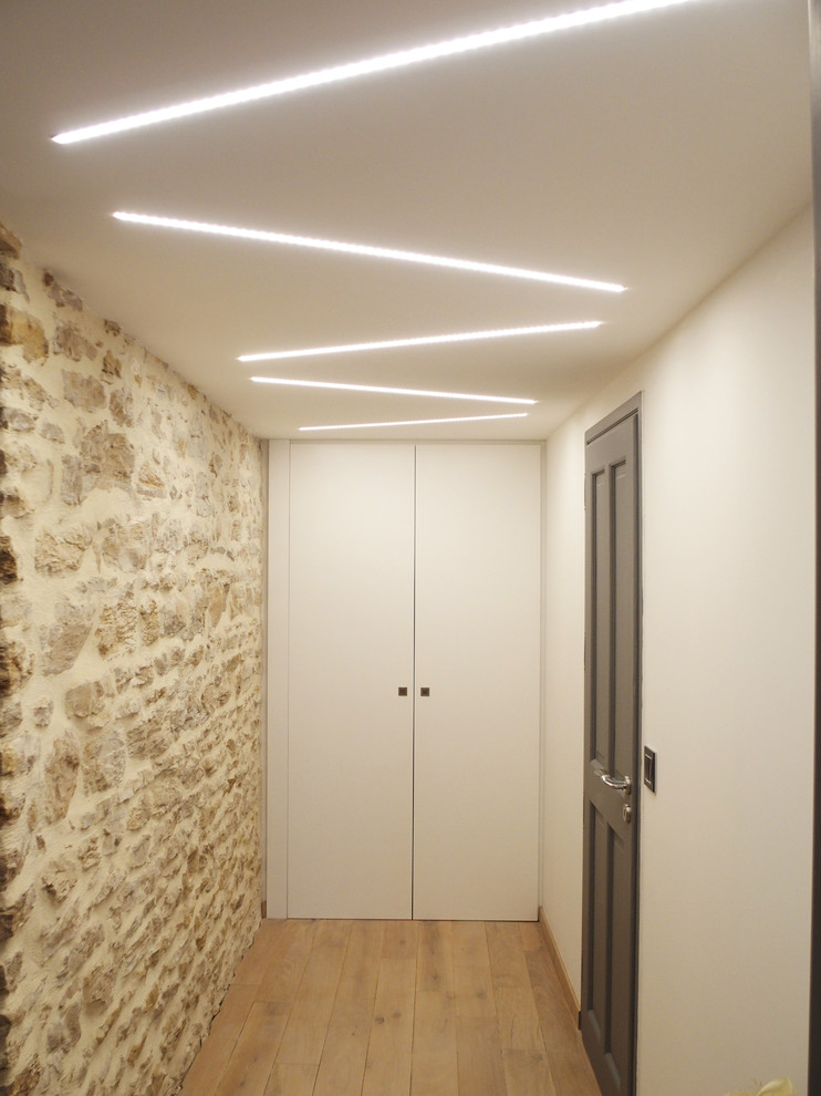 This is an example of a mid-sized contemporary hallway in Grenoble with white walls, light hardwood floors and beige floor.