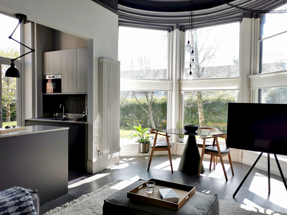 Diseño de salón abierto y gris y negro escandinavo de tamaño medio sin chimenea con paredes blancas, suelo laminado, televisor independiente y suelo marrón