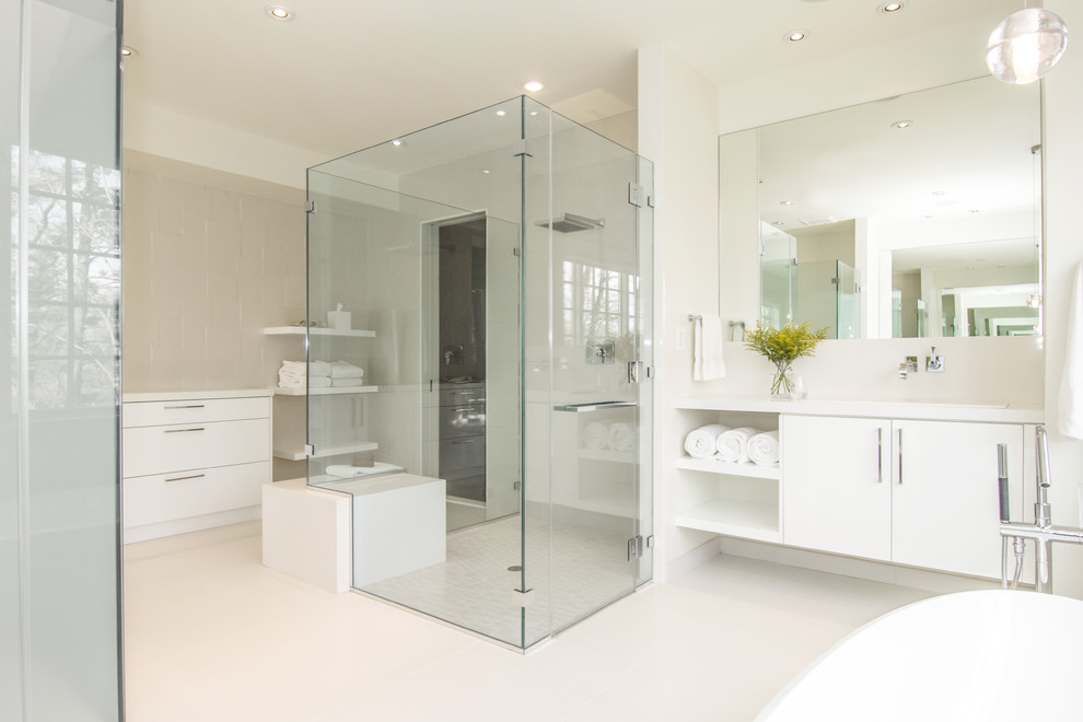 Large modern master bathroom in DC Metro with flat-panel cabinets, white cabinets, a freestanding tub, white tile, white walls, an undermount sink, solid surface benchtops, a curbless shower, a two-piece toilet, stone tile, cement tiles, white floor and a hinged shower door.