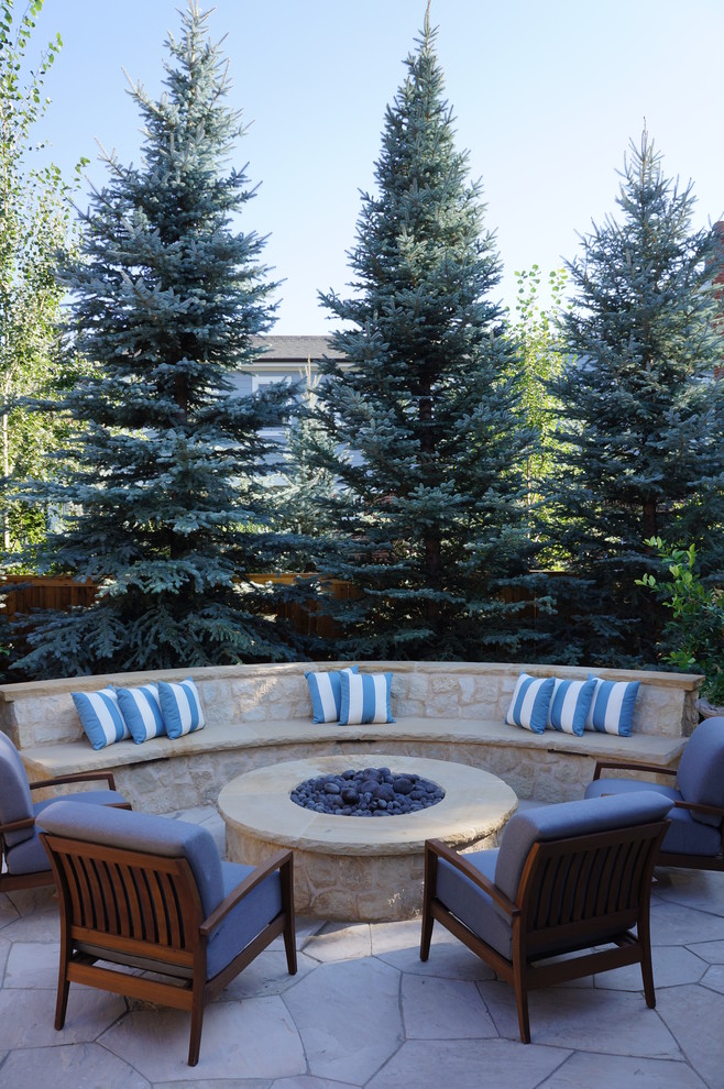 Photo of a mid-sized mediterranean side yard patio in Denver with a fire feature, natural stone pavers and no cover.