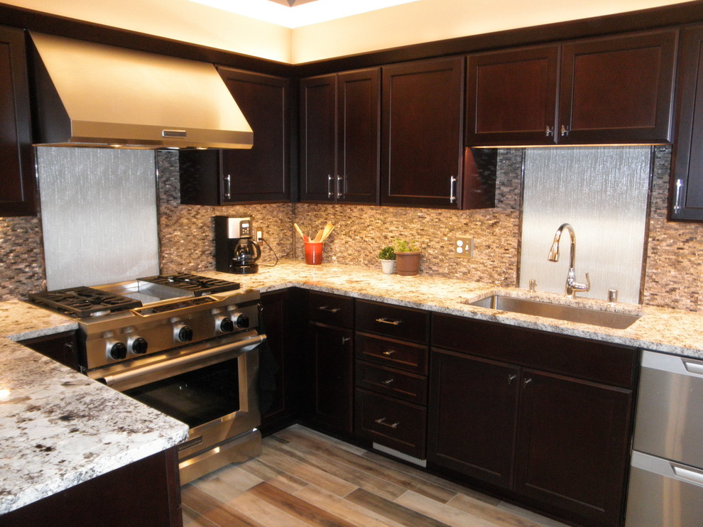 Transitional eat-in kitchen photo in Milwaukee with a peninsula, dark wood cabinets, granite countertops, multicolored backsplash, glass sheet backsplash and stainless steel appliances