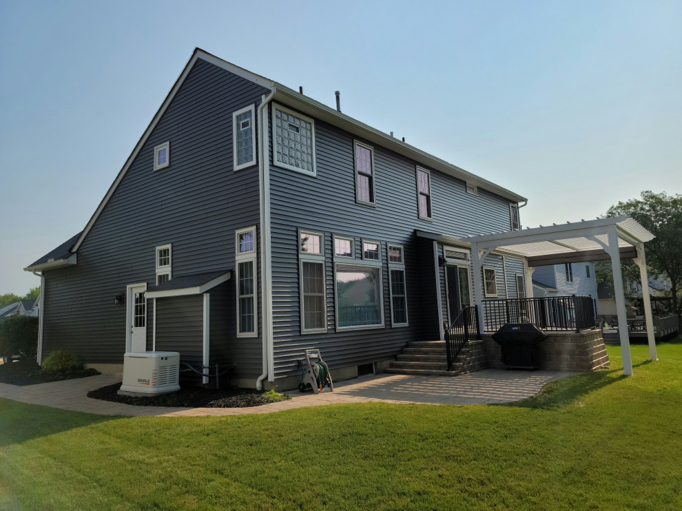 Photo of a large traditional two-storey grey house exterior in Cleveland with vinyl siding, a gable roof, a shingle roof, a black roof and clapboard siding.