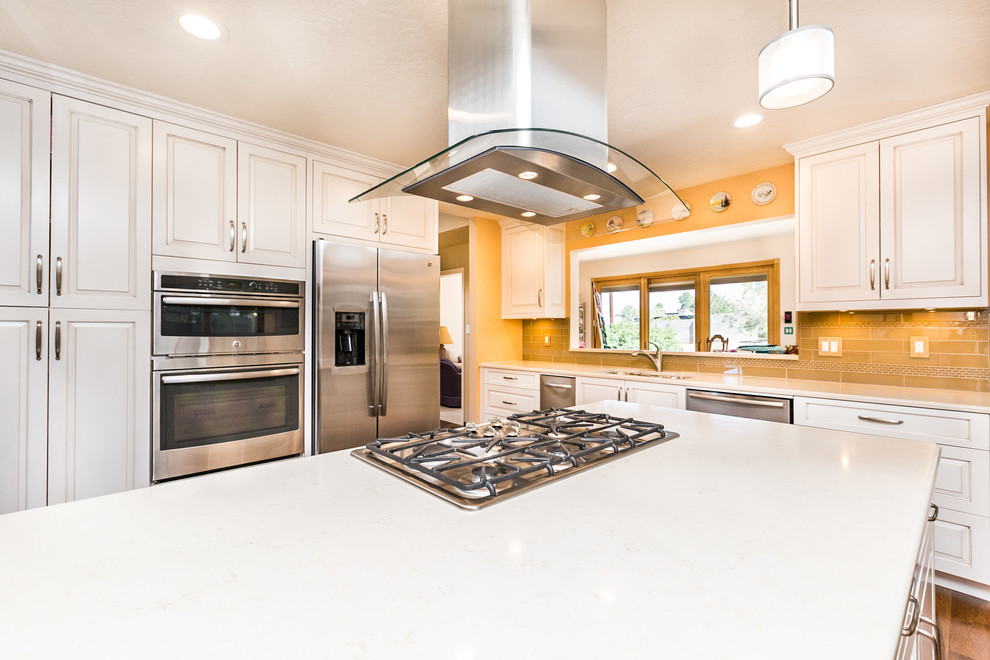 Mid-sized transitional u-shaped medium tone wood floor enclosed kitchen photo in Albuquerque with a double-bowl sink, raised-panel cabinets, white cabinets, quartz countertops, beige backsplash, subway tile backsplash, stainless steel appliances and an island