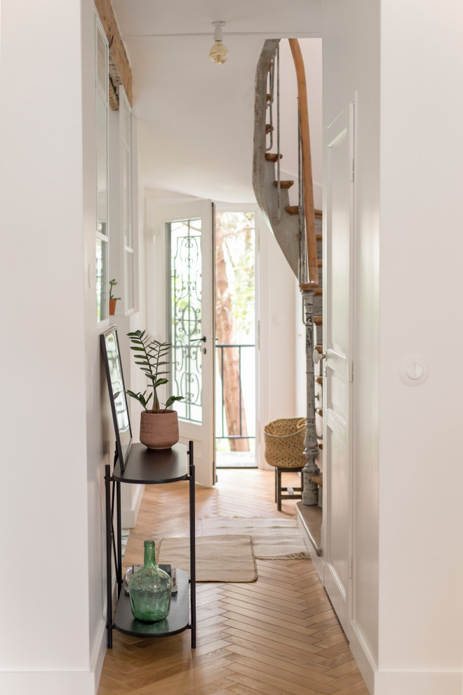 Design ideas for a mid-sized hallway in Paris with white walls and light hardwood floors.