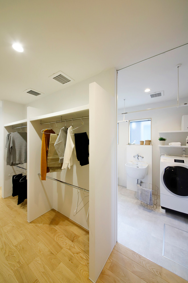 На фото: гардеробная комната унисекс в стиле модернизм с паркетным полом среднего тона, потолком с обоями, открытыми фасадами, белыми фасадами и коричневым полом