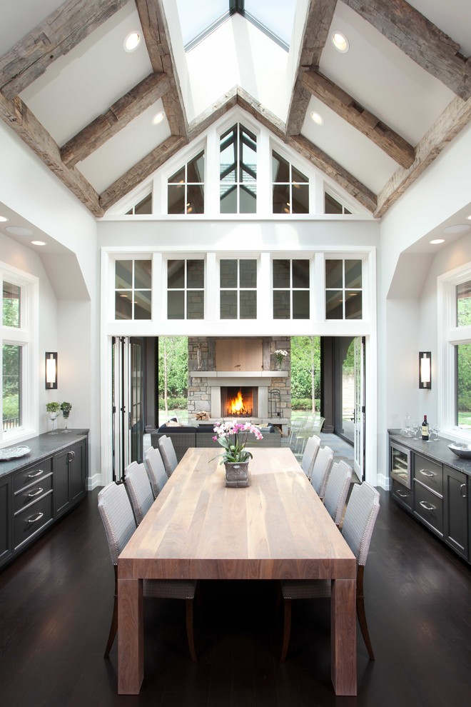 Large transitional kitchen/dining combo in Minneapolis with white walls, dark hardwood floors, a standard fireplace, a stone fireplace surround and brown floor.