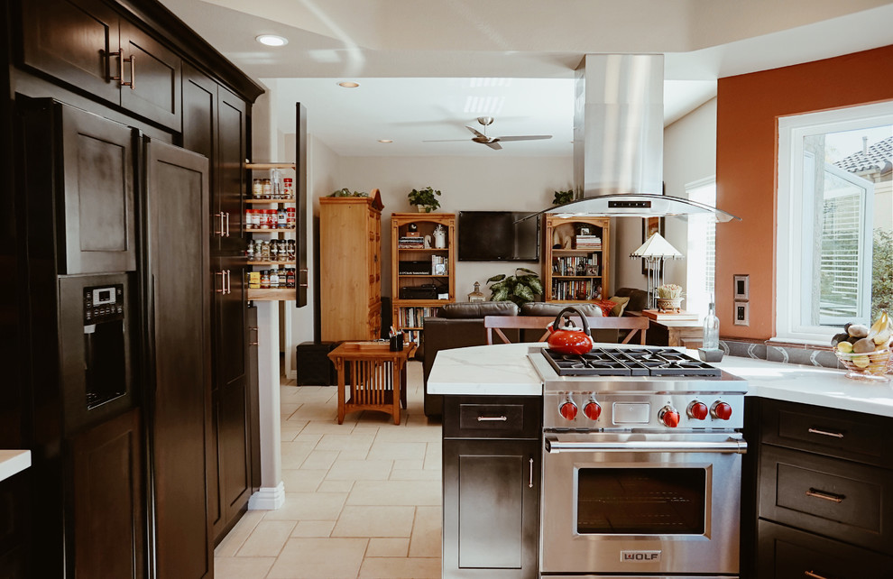 Mid-sized transitional u-shaped separate kitchen in Orange County with a farmhouse sink, shaker cabinets, dark wood cabinets, quartz benchtops, metal splashback, stainless steel appliances, ceramic floors, beige floor and a peninsula.