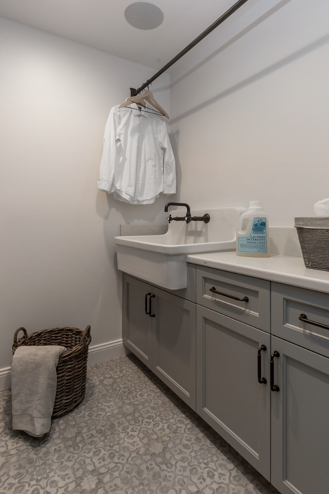 Inspiration for a mid-sized utility room in San Francisco with a drop-in sink, glass-front cabinets, medium wood cabinets, quartz benchtops, white walls, ceramic floors, a side-by-side washer and dryer, multi-coloured floor and white benchtop.