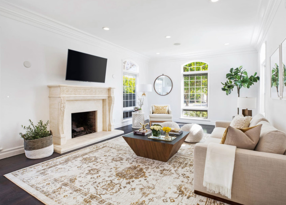 This is an example of a large classic formal enclosed living room in San Diego with white walls, dark hardwood flooring, a standard fireplace, a stone fireplace surround, a wall mounted tv and brown floors.