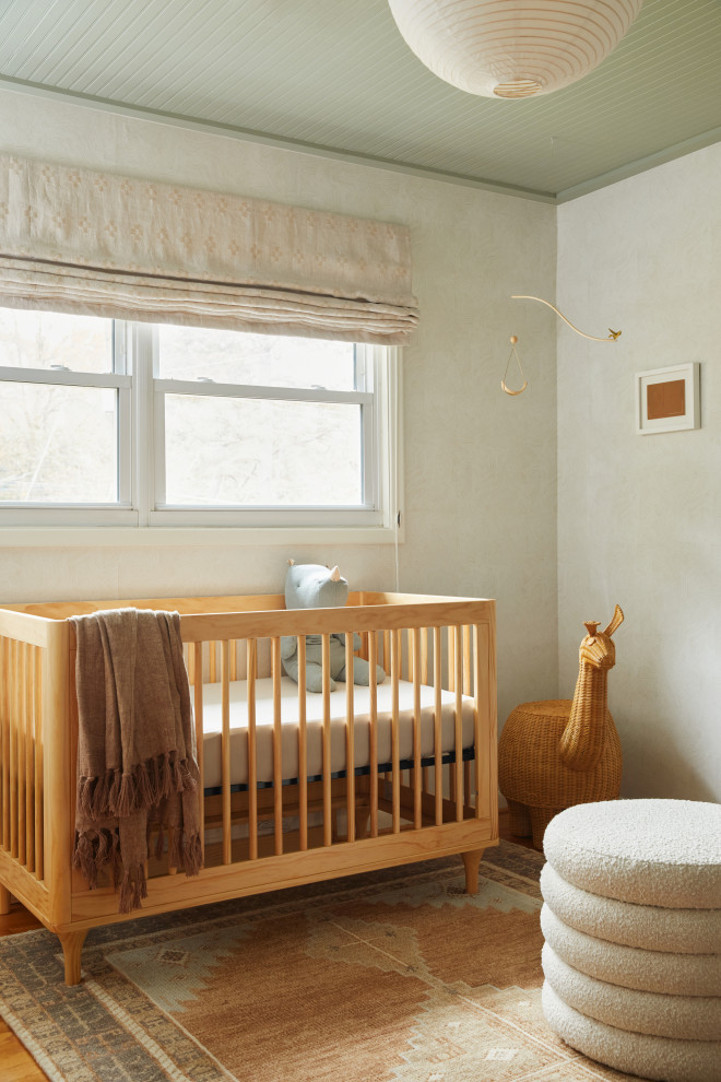 Immagine di una piccola cameretta per neonati neutra american style con pareti beige, pavimento in legno massello medio, pavimento marrone, soffitto in legno e carta da parati