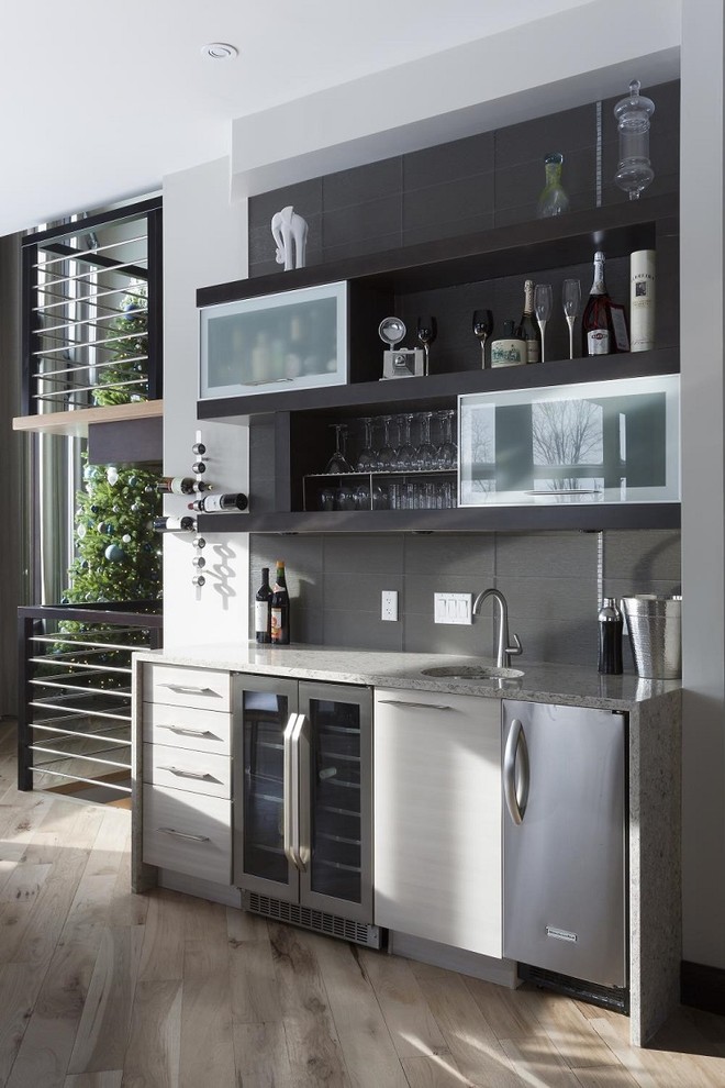 Inspiration for a small contemporary single-wall wet bar in San Diego with an undermount sink, flat-panel cabinets, grey cabinets, quartz benchtops, grey splashback, light hardwood floors and grey floor.