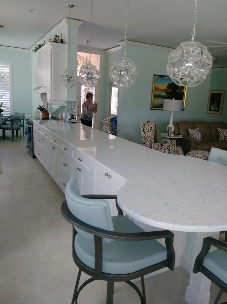 Inspiration for a transitional galley kitchen remodel with shaker cabinets, white cabinets, quartz countertops, glass tile backsplash and stainless steel appliances