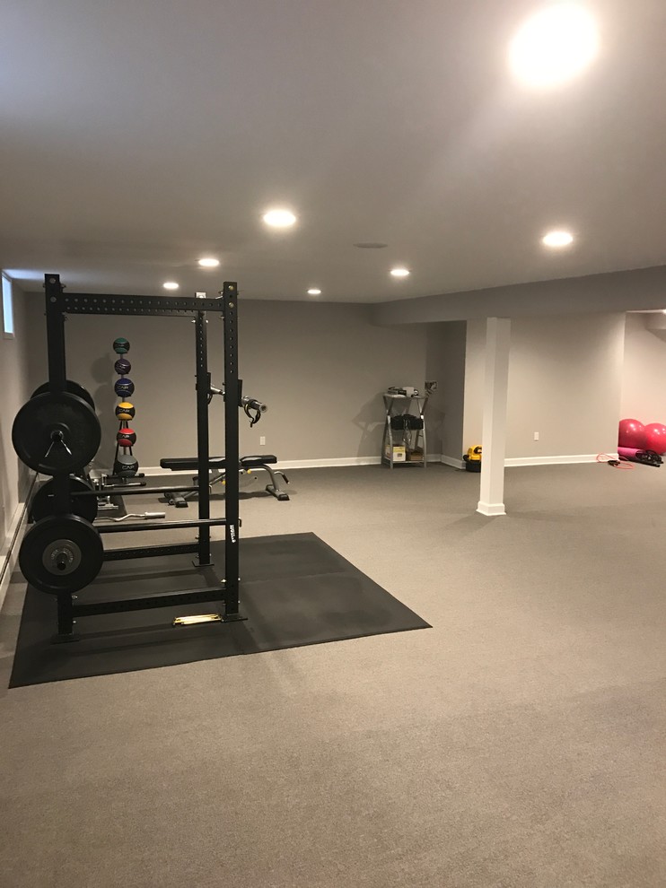 This is an example of a large traditional home weight room in New York with grey walls, carpet and grey floor.
