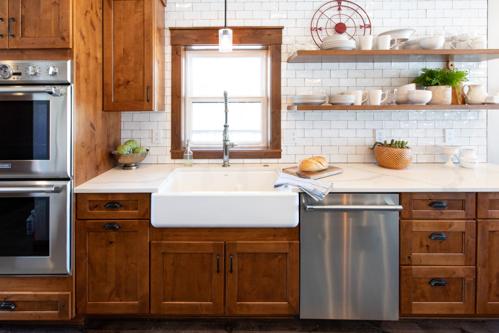 Design ideas for a large country u-shaped eat-in kitchen in Portland with a farmhouse sink, shaker cabinets, medium wood cabinets, quartz benchtops, white splashback, subway tile splashback, stainless steel appliances, concrete floors, with island, grey floor and white benchtop.