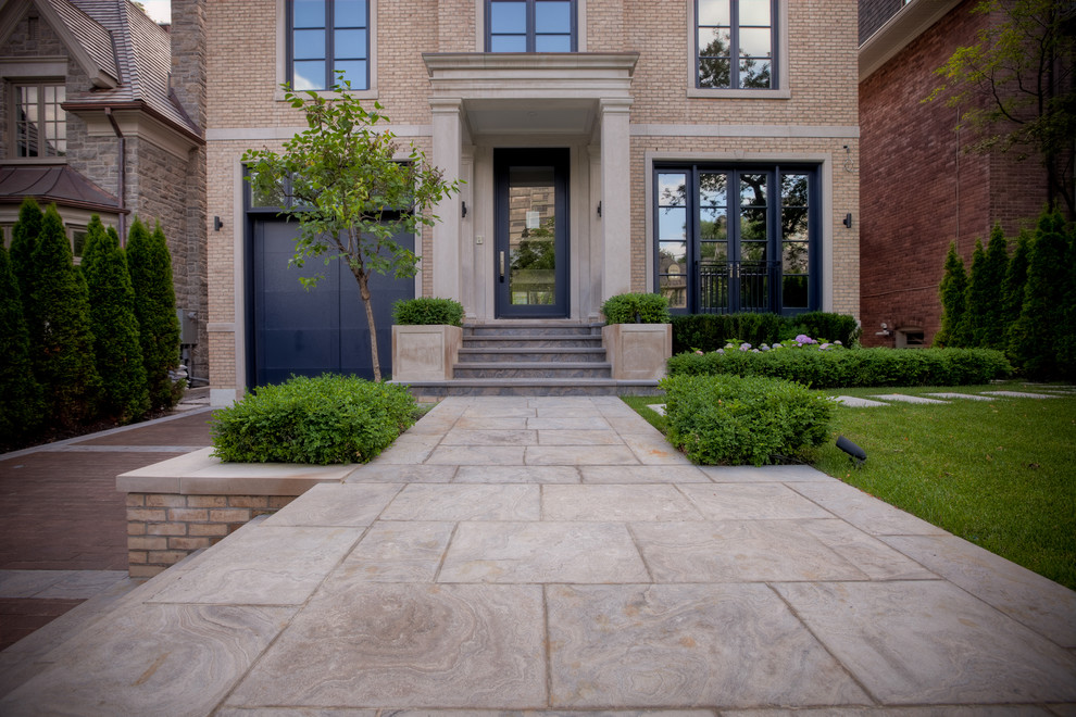 Inspiration for a small traditional front yard full sun driveway for summer in Toronto with a retaining wall and natural stone pavers.